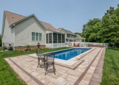 This project involved the installation of a Claremont Fiberglass Pool with a paver pool deck tying into a paver patio. Add-ons included a seat wall, pergola, and LED exterior lighting. Glen Allen, VA | Pool & Deck Construction