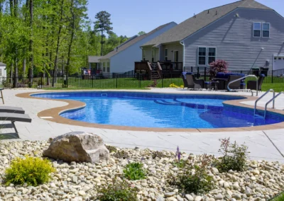 Unique shaped freeform swimming pool with concrete patio.