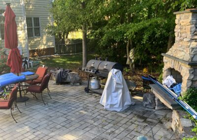 Before photo of an old paver patio with stone fire place.