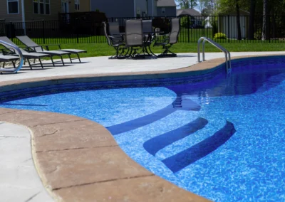 Unique shaped freeform swimming pool with steps going into pool.