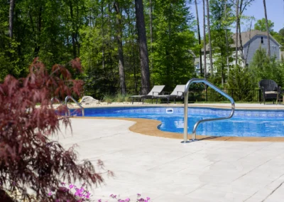 Unique shaped freeform swimming pool with concrete patio.