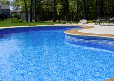 Unique shaped freeform swimming pool with steps going into pool.