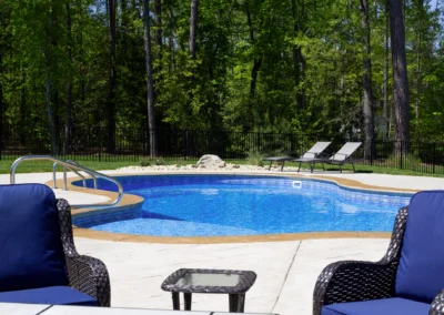 Unique shaped freeform swimming pool with concrete patio.