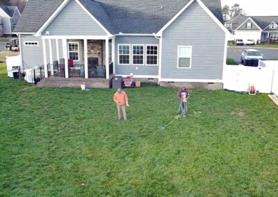 Medium sized grey house with backyard. People standing in yard.