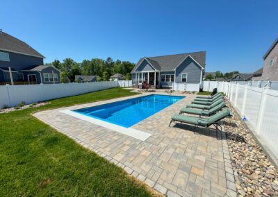 Rectangle pool with patio deck in backyard.