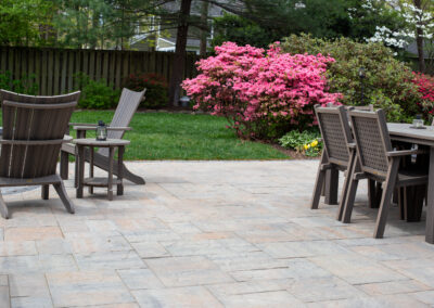 Paver patio with pink flowers and seating areas.