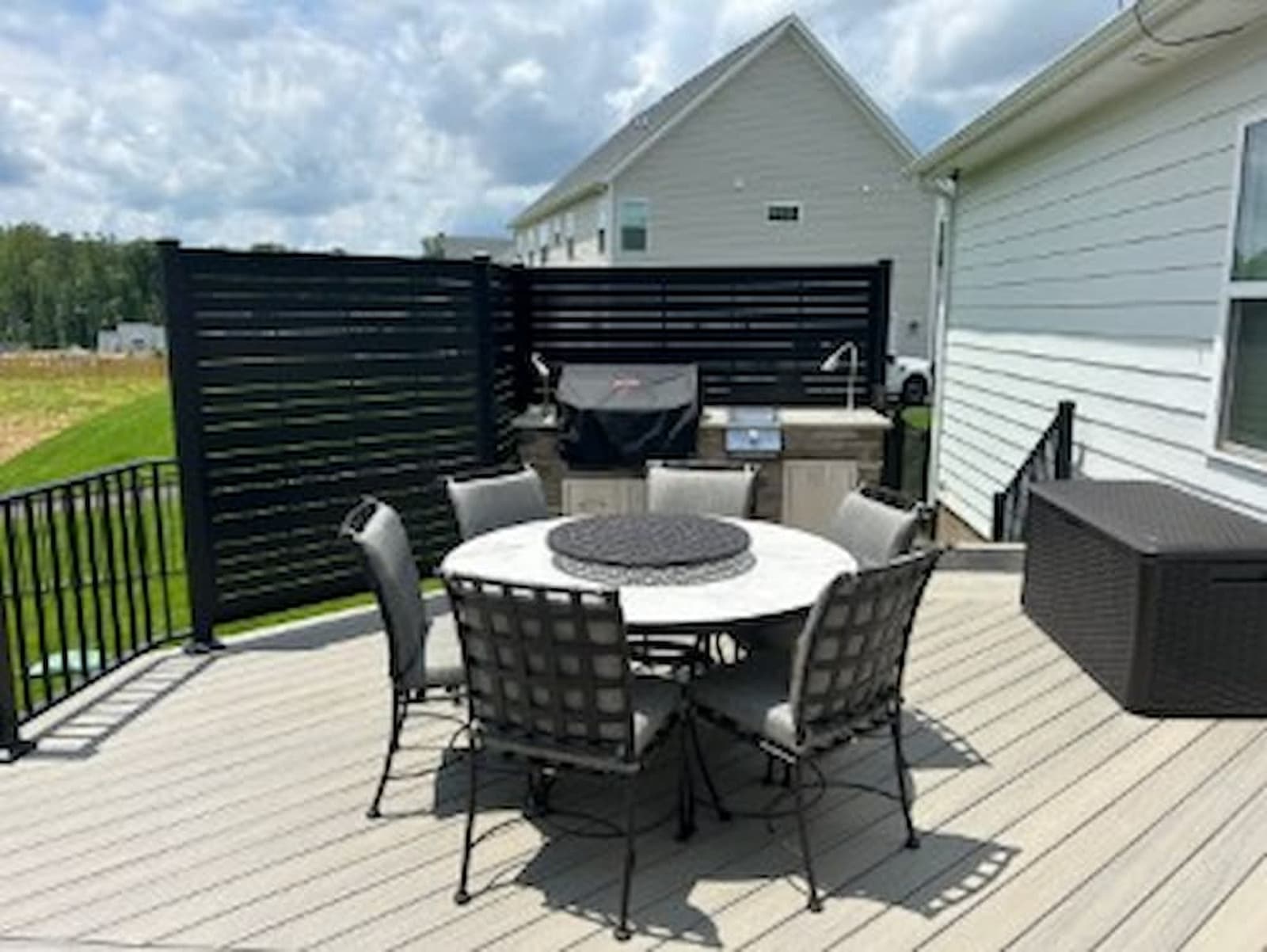Low-maintenance composite decking surrounding a round dining table, demonstrating the modern, durable material versus traditional lumber.